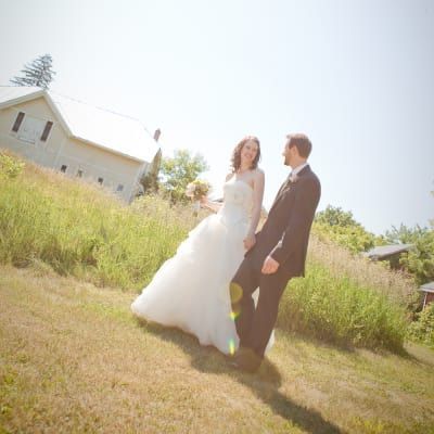 A bride and groom are standing in a field holding hands