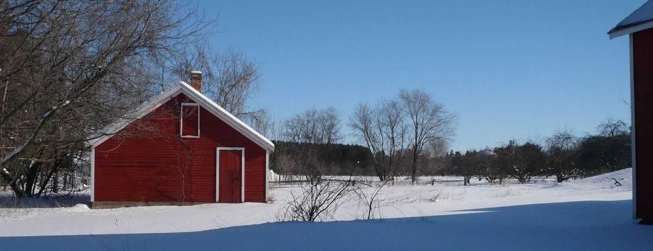 A red barn is sitting in the middle of a snowy field.