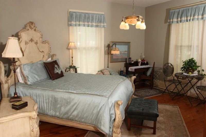 A bedroom with a bed , nightstand , desk and chairs.