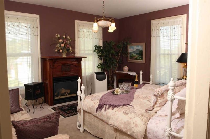 A bedroom with purple walls and a fireplace