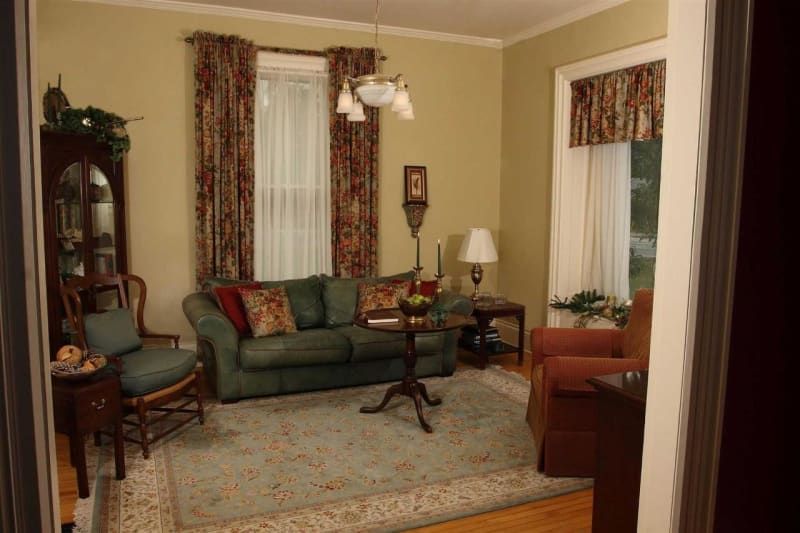 A living room with a green couch and chairs