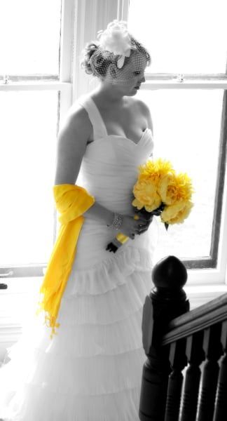 A woman in a white dress is holding a bouquet of yellow flowers