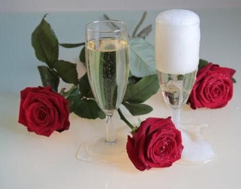 Two glasses of champagne and red roses on a table