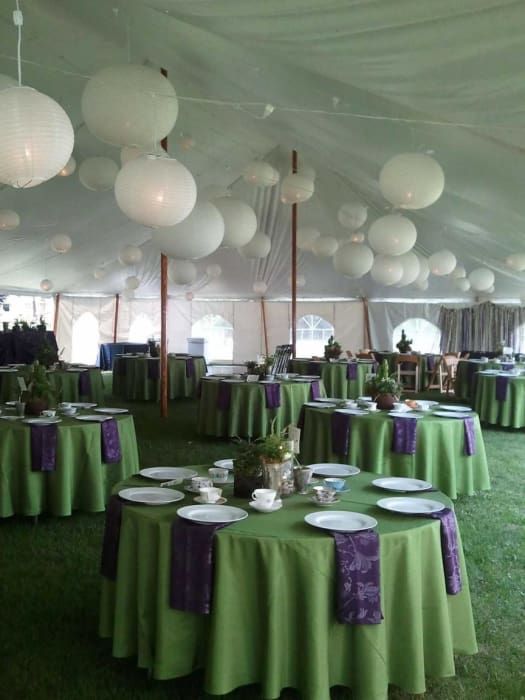 A large tent with green tables and purple napkins