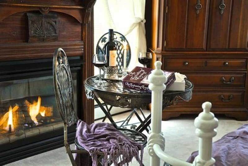 A bottle of wine sits on a table in front of a fireplace.