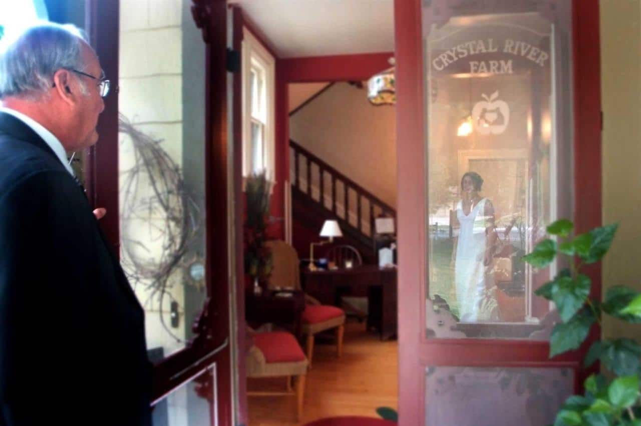 A man standing in front of a door that says coastal river farm