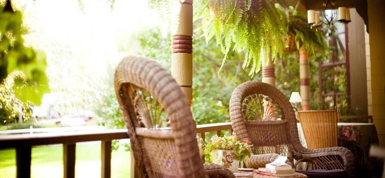 A wicker chair is sitting on a porch next to a table.