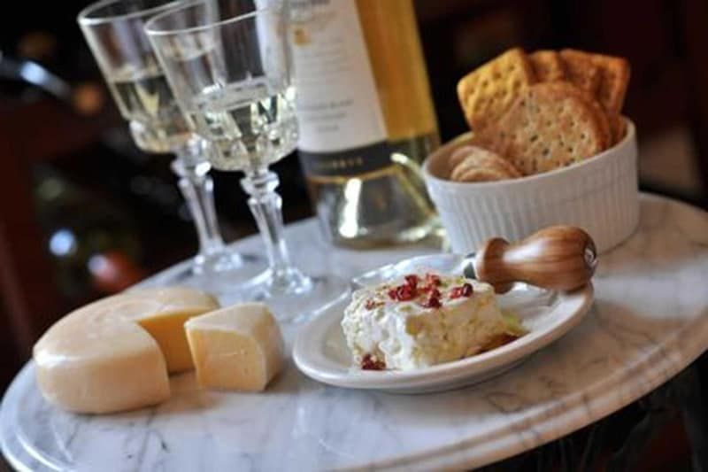A table topped with cheese , crackers and wine glasses.