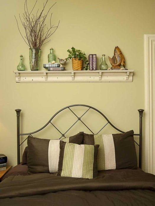 A bedroom with a bed and a shelf above it