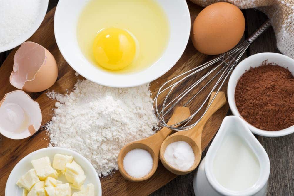 A wooden cutting board topped with bowls of ingredients for baking.