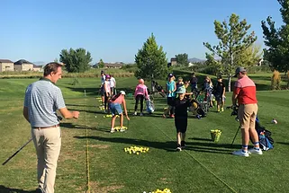 A group of people are practicing golf on a golf course.
