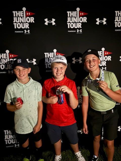 A young boy wearing a white hat and gloves is swinging a golf club.