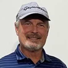 A man wearing a hat and a striped shirt is smiling.