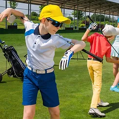 A boy is swinging a golf club on a golf course.