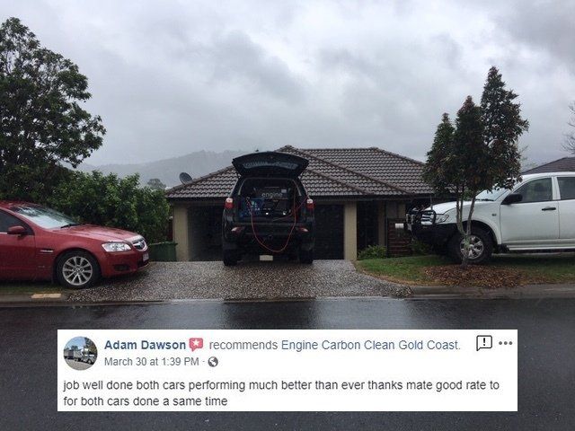 A red car is parked in front of a house with the trunk open.