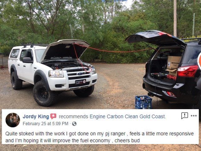 A white truck with the hood open is parked next to a black suv.