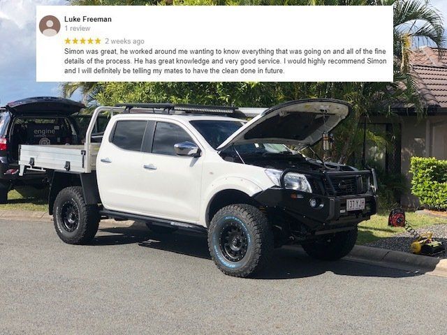 A white truck with the hood open is parked on the side of the road.