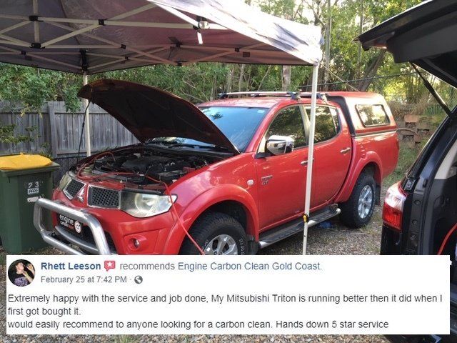 A red truck is parked under a tent with the hood open