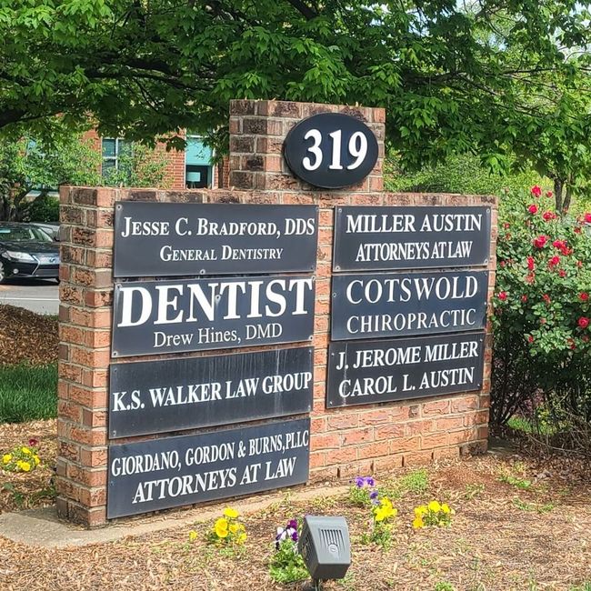A sign for a dentist is sitting in front of a building.