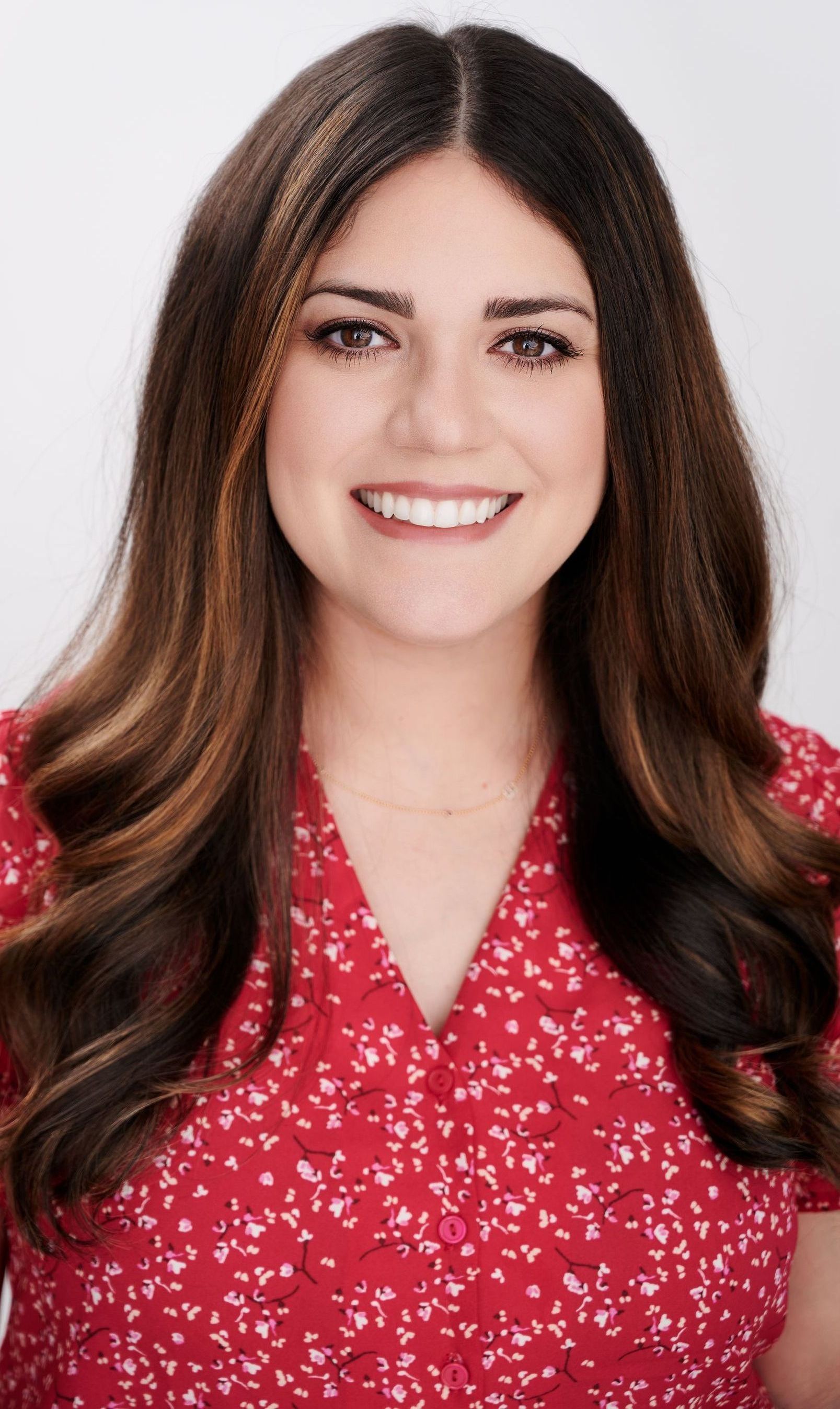 A woman in a suit and blue shirt is smiling for the camera