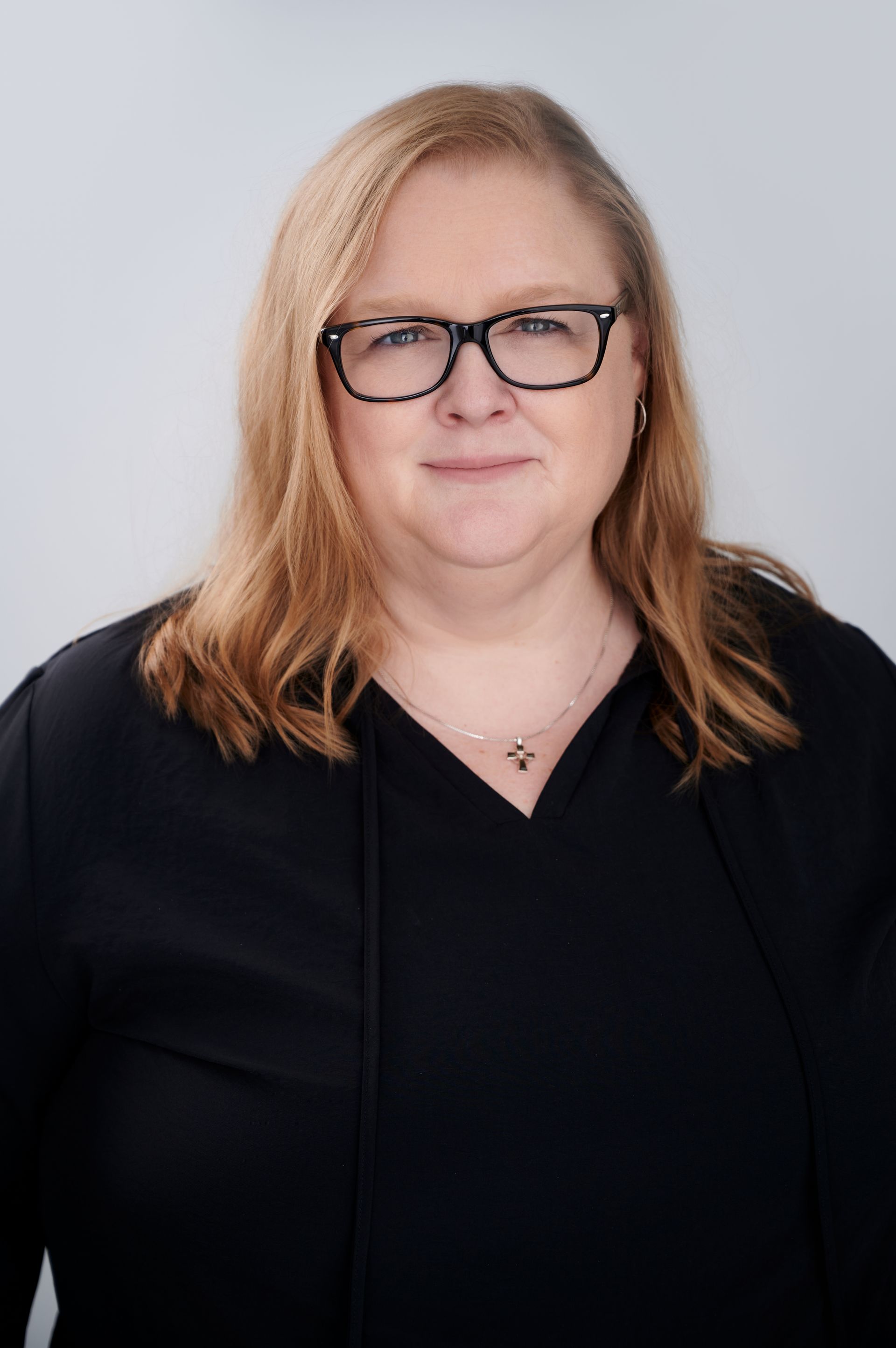 A woman wearing a black jacket and a cross necklace