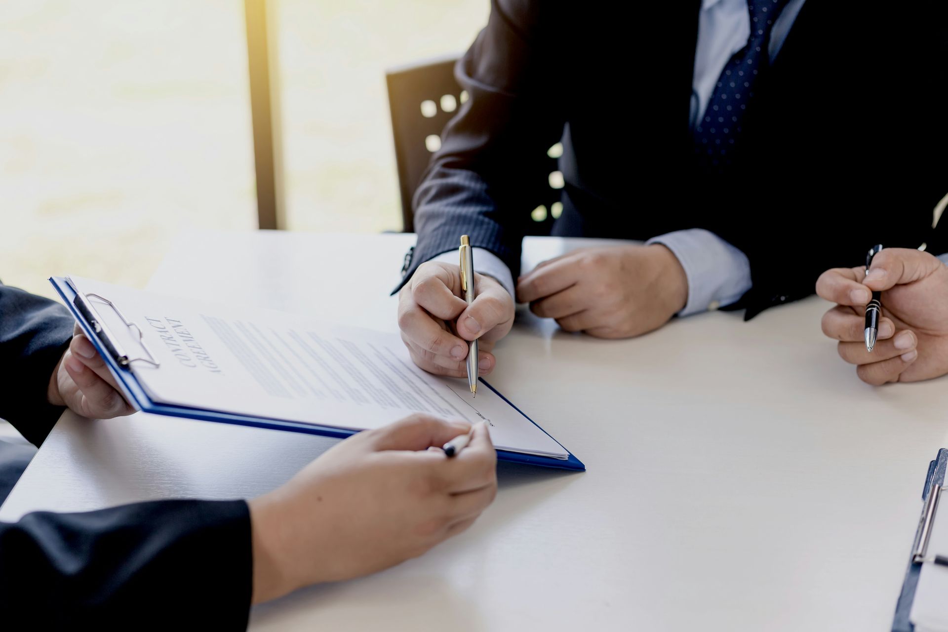 A group of people are sitting at a table signing a document.