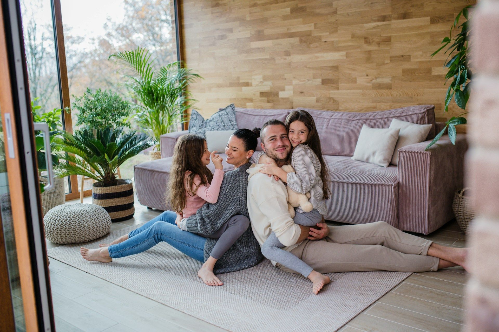 A family is sitting on the floor in a living room.