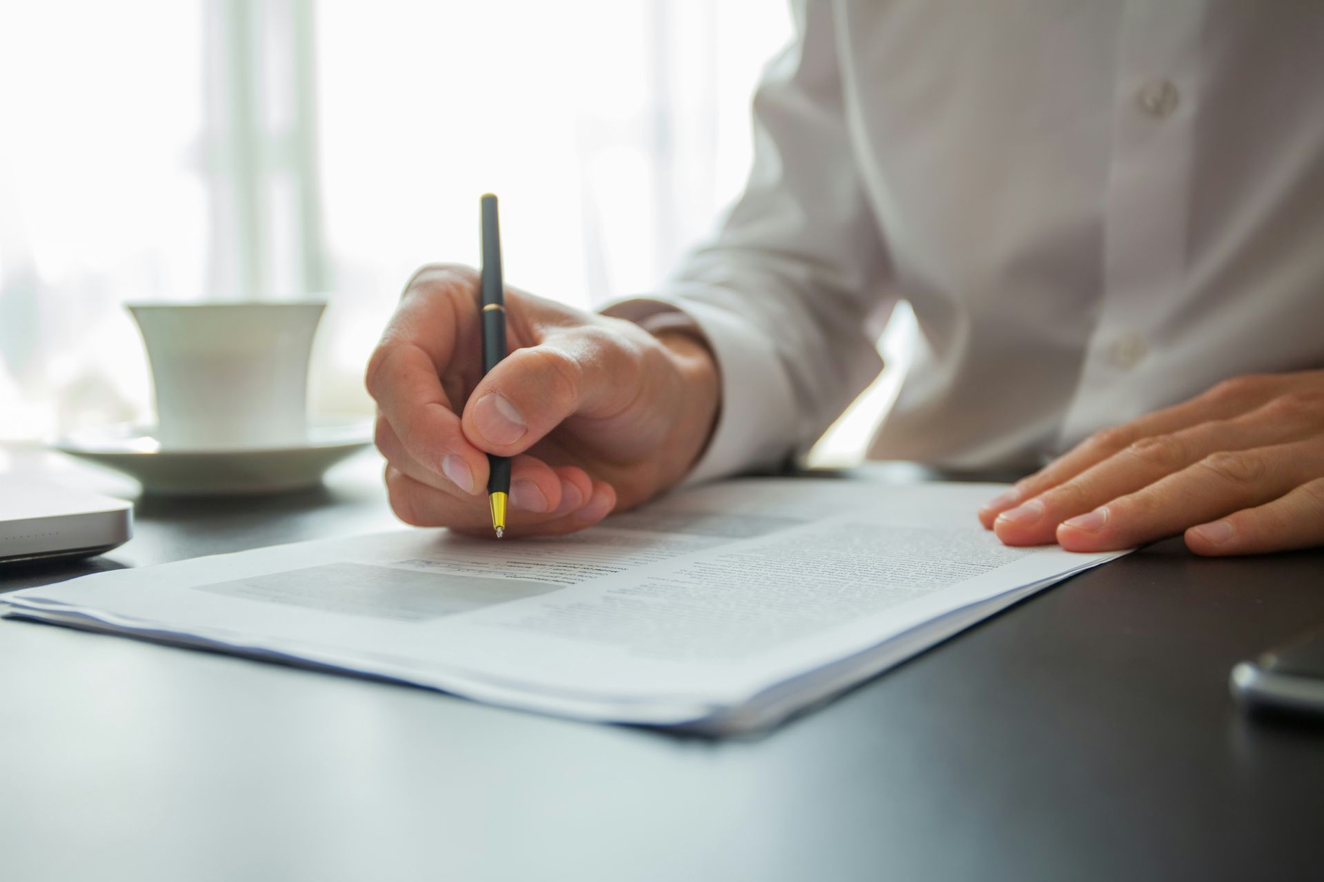 A person is writing on a piece of paper with a pen.