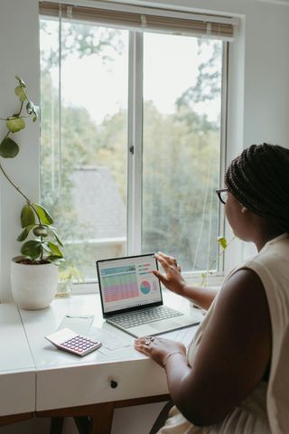 A woman is sitting at a desk using a laptop computer.