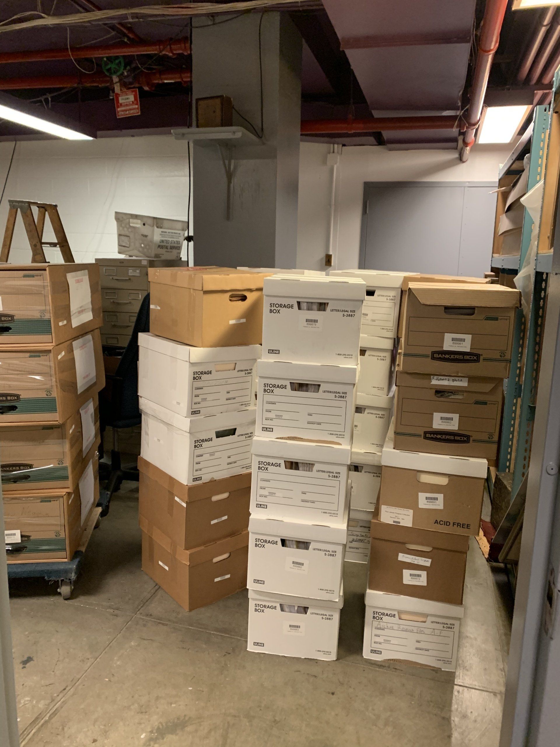Boxes stacked in a storage room. Brown and white boxes are piled high.