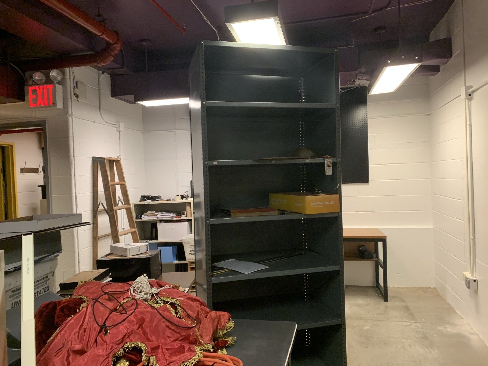 Dark gray shelving unit in a room with a red costume.