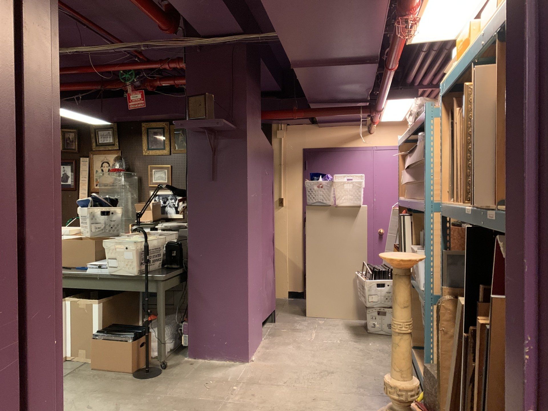 Purple-painted storage area with shelves, artwork, and a workspace with various supplies.