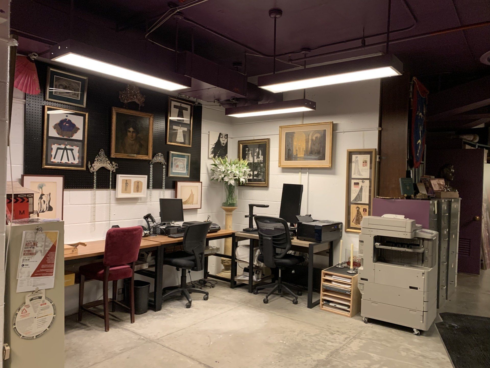 Office space with desks, computers, art on the wall, and a purple ceiling.