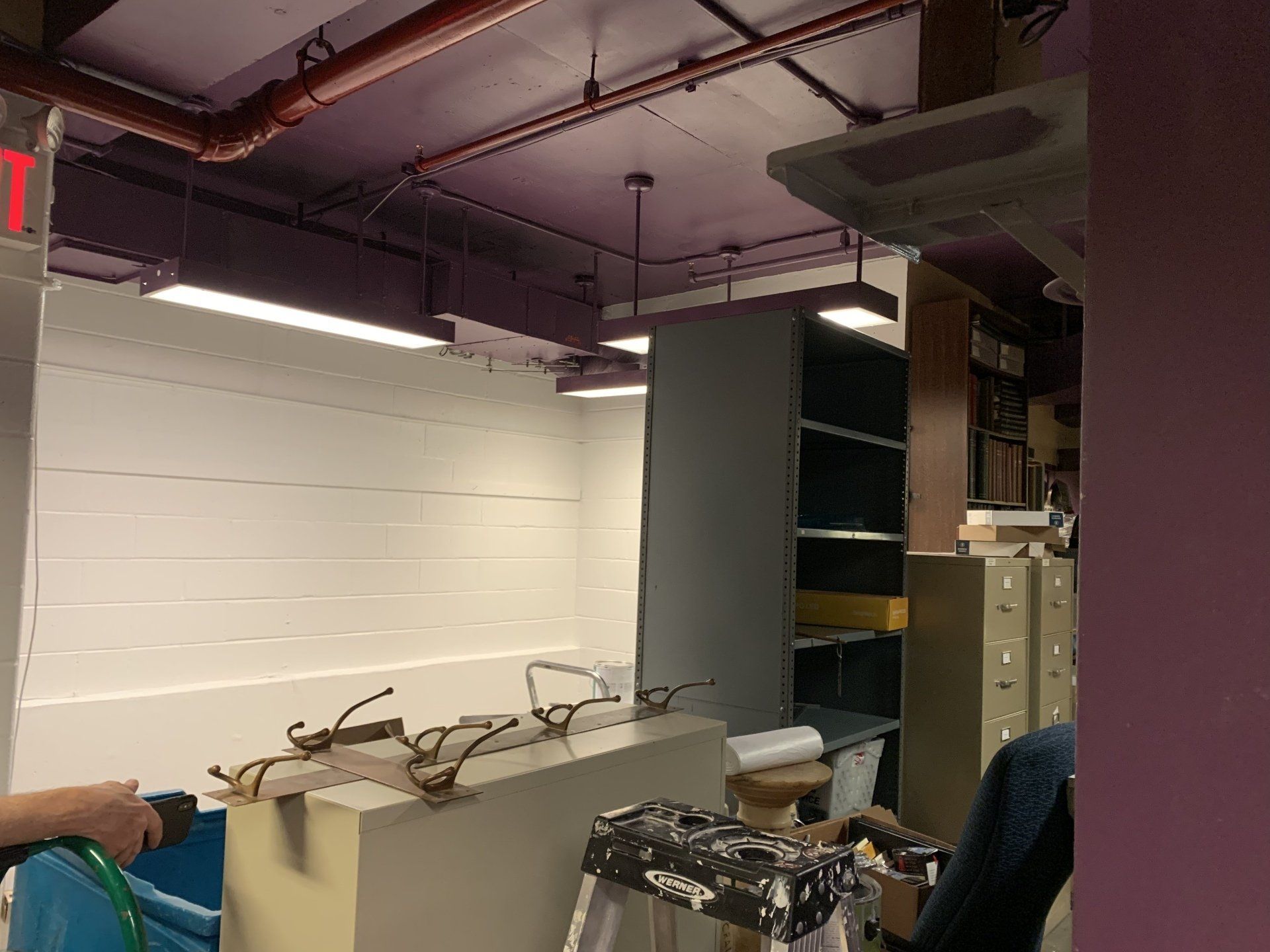 Interior with white and purple walls, gray shelves, and a person holding a hose.