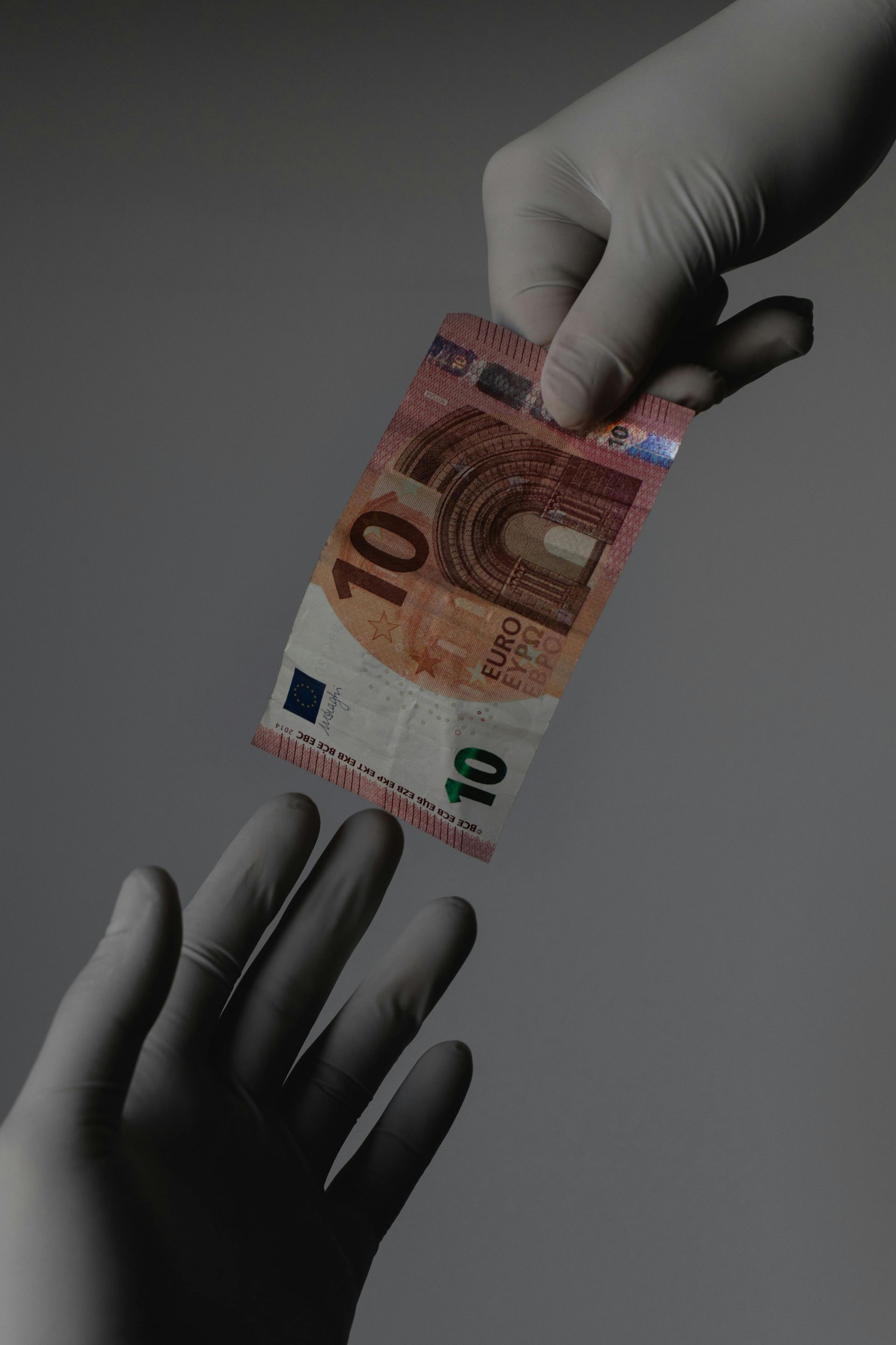 A person is holding a 10 euro bill in their hand