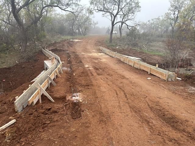 A dirt road with a wooden fence in the middle of it.