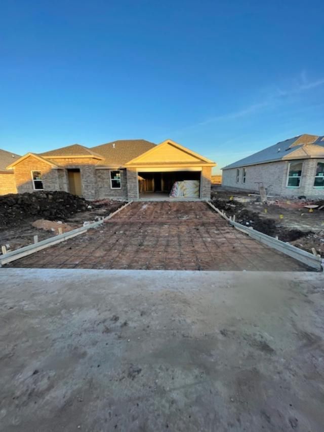 A house under construction with a concrete driveway in front of it.