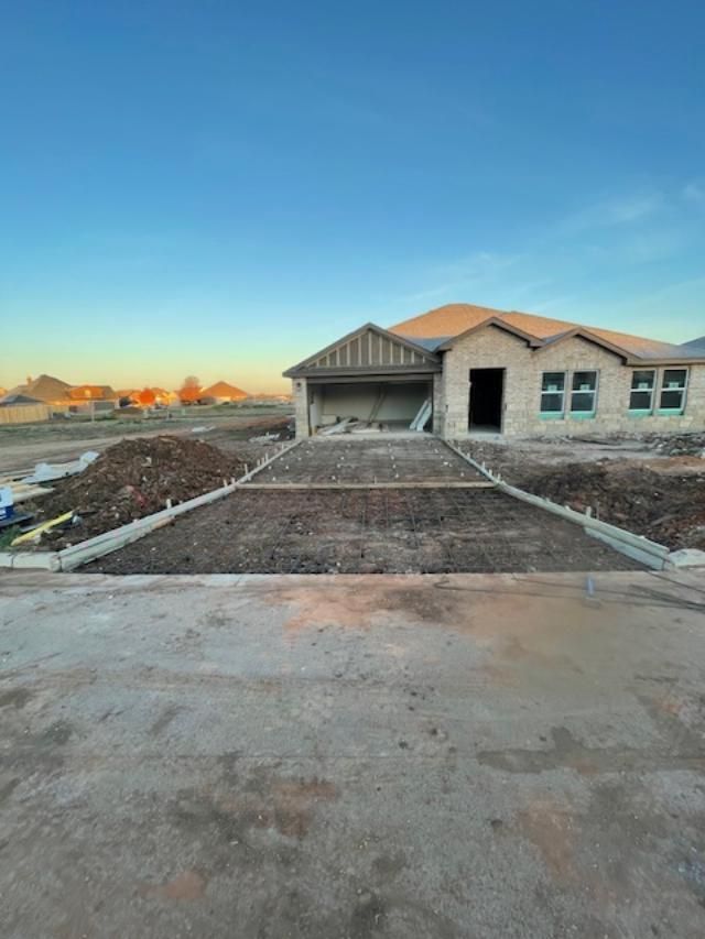 A house under construction with a concrete driveway in front of it.