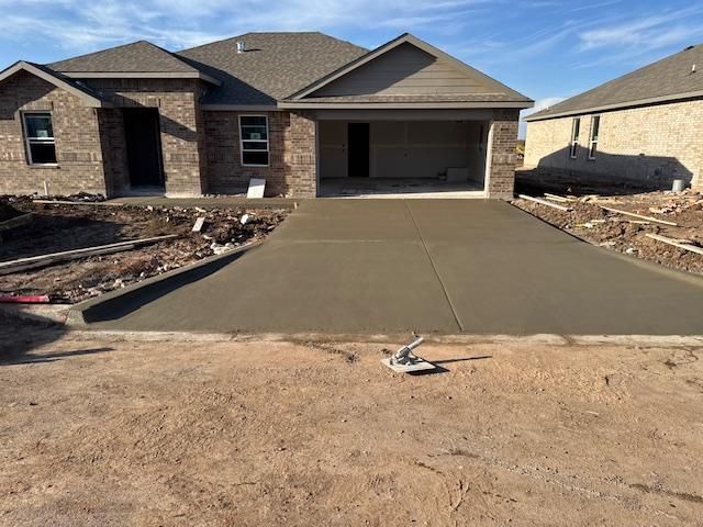 A brick house with a concrete driveway in front of it