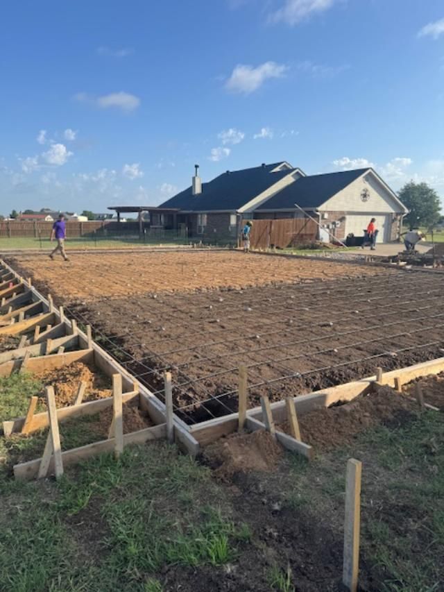 A large dirt field with a house in the background is being built.