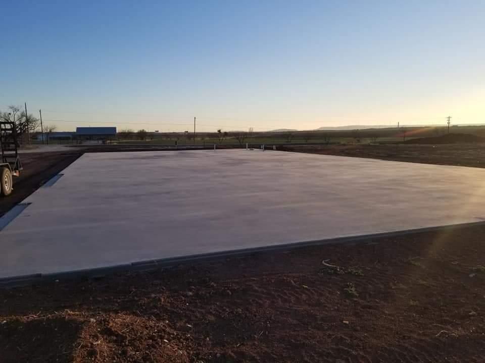 A large concrete floor is being built in a field.