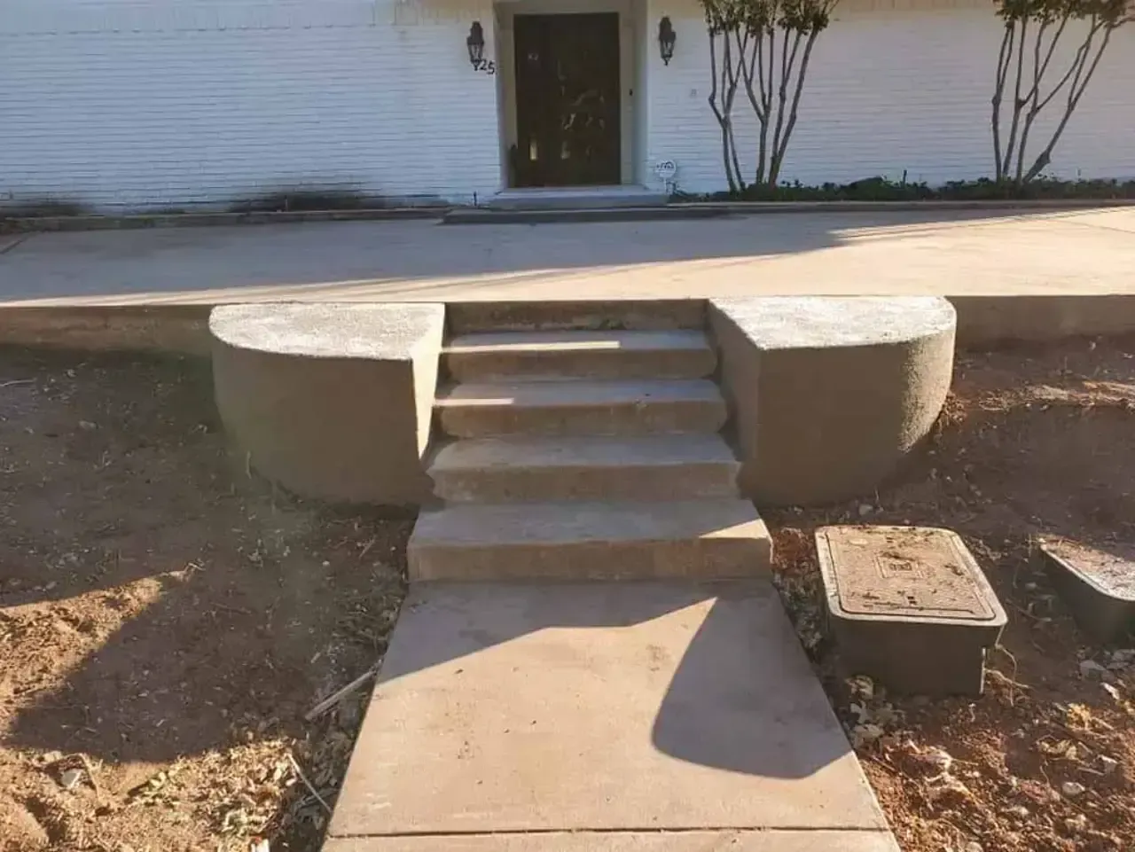 A concrete walkway with stairs leading up to a house.