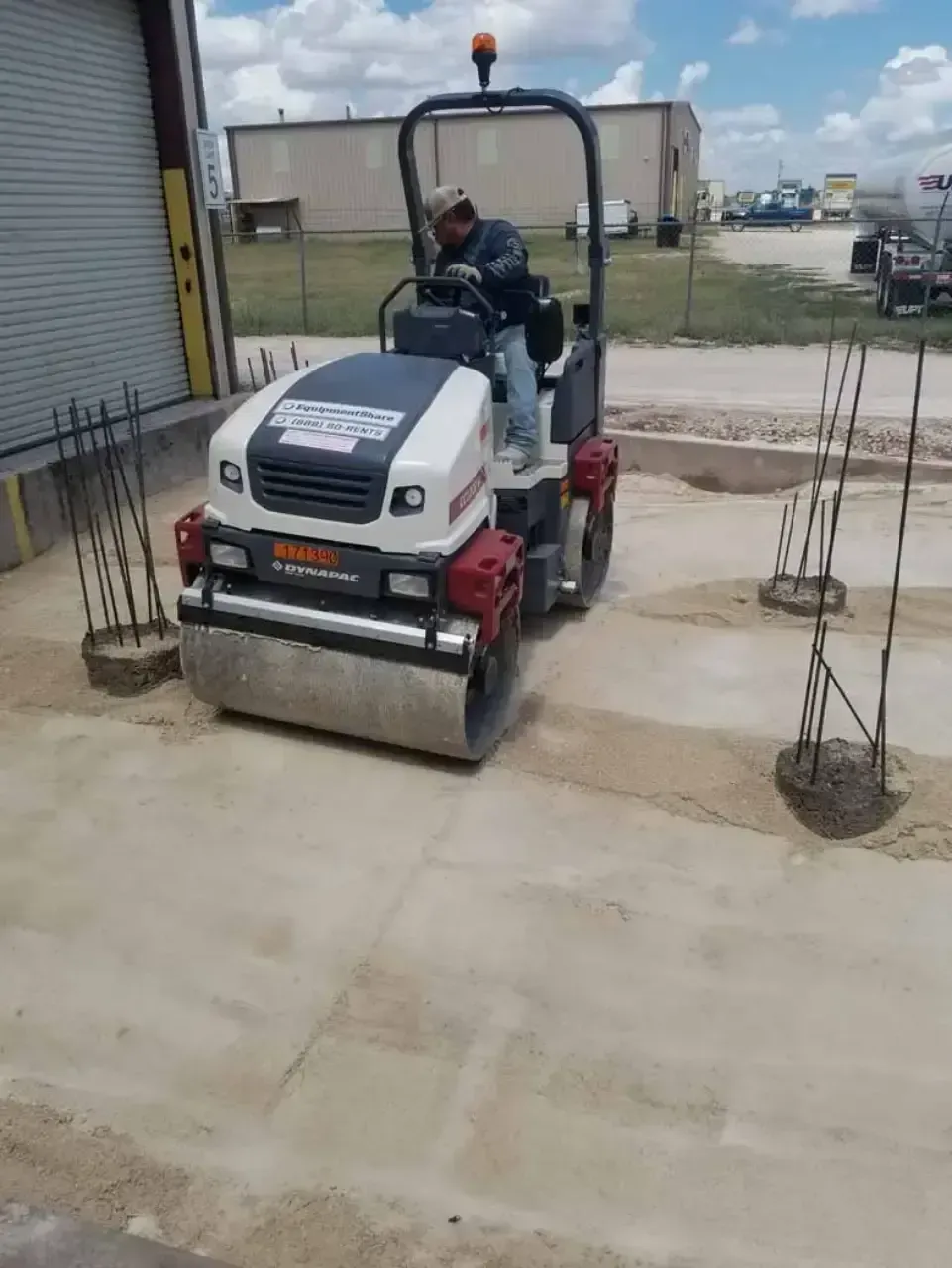 A man is driving a roller on a dirt road.