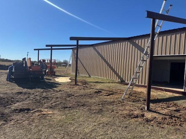 A ladder is sitting in front of a building in a field.