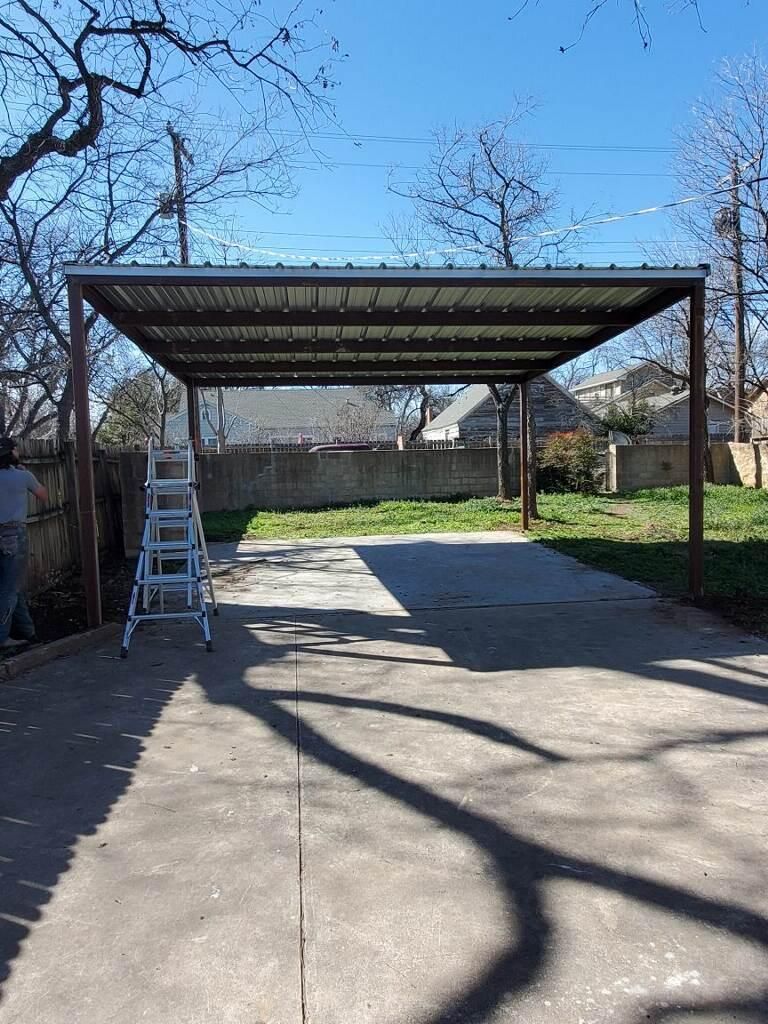 A carport with a ladder in the middle of a driveway.