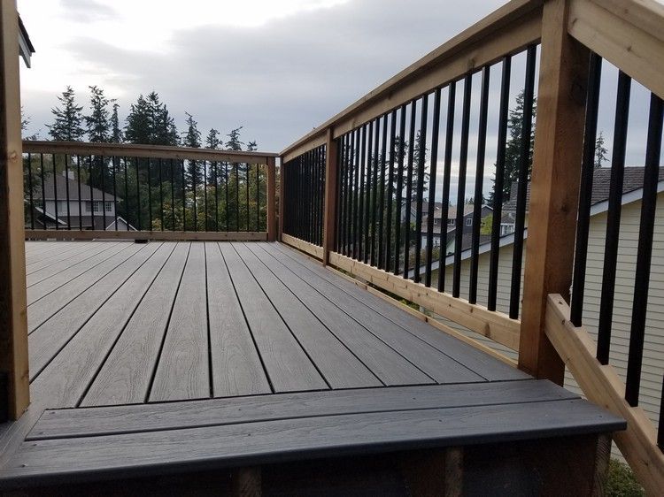A wooden deck with a black railing and stairs