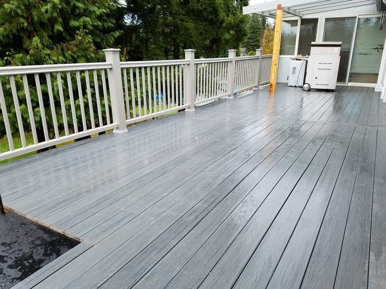 A gray deck with a white railing and a ladder on it.