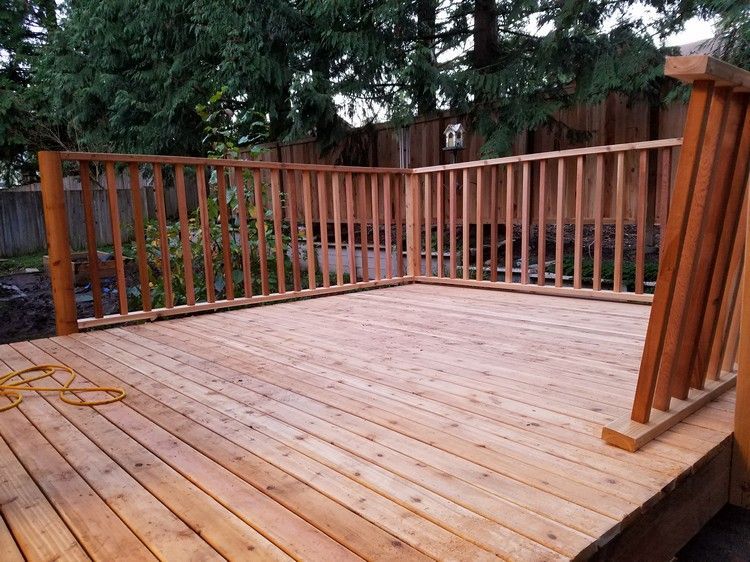 A wooden deck with a railing and trees in the background