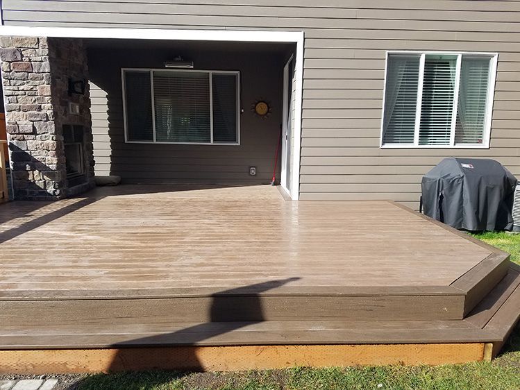 A large wooden deck is in front of a house.