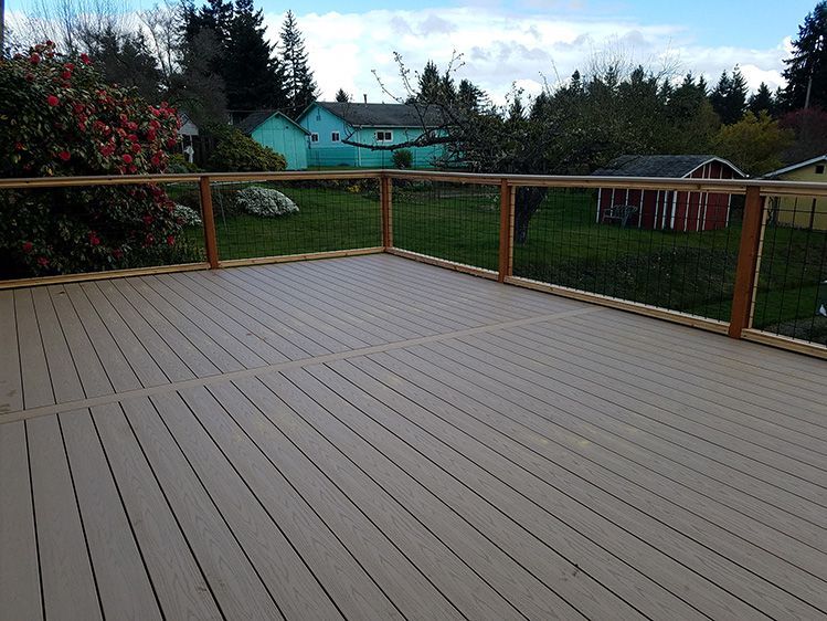 A large wooden deck with a wooden railing and a red barn in the background.